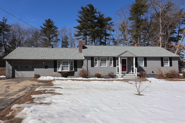 single story home with a chimney, a garage, driveway, and roof with shingles