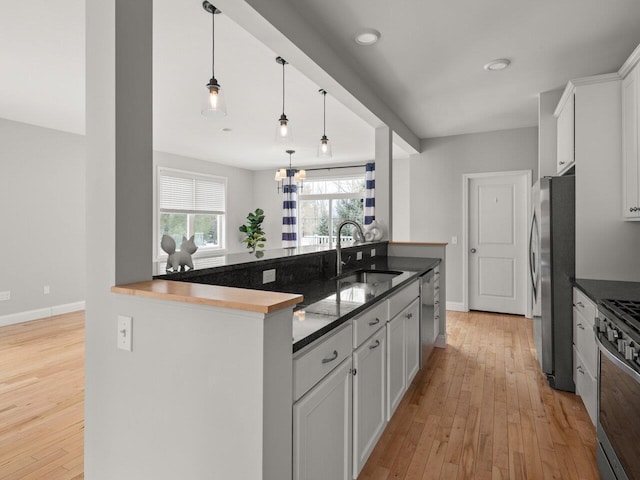 kitchen featuring a sink, white cabinetry, light wood-style floors, appliances with stainless steel finishes, and baseboards