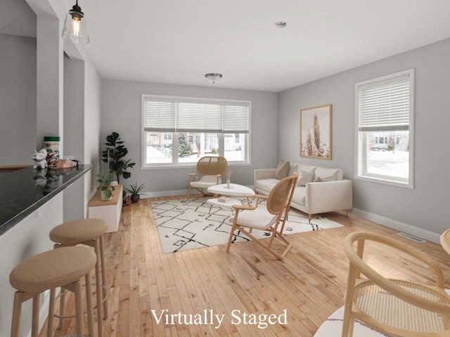 living area featuring light wood-style floors, visible vents, and baseboards