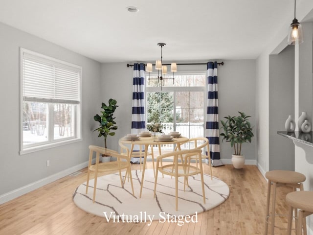 dining space with an inviting chandelier, light wood-style flooring, and baseboards