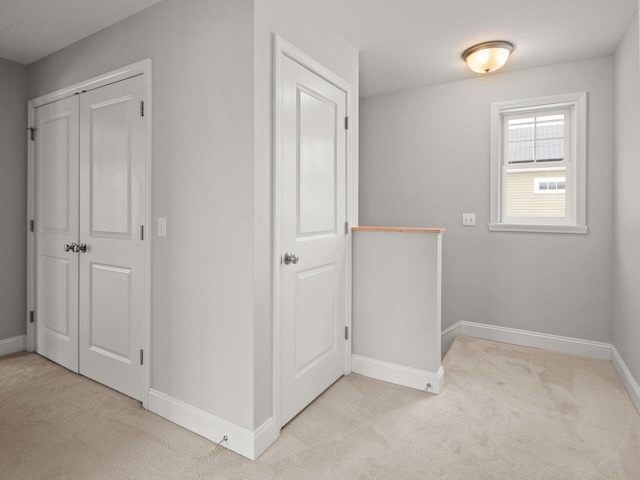 corridor featuring baseboards and light colored carpet