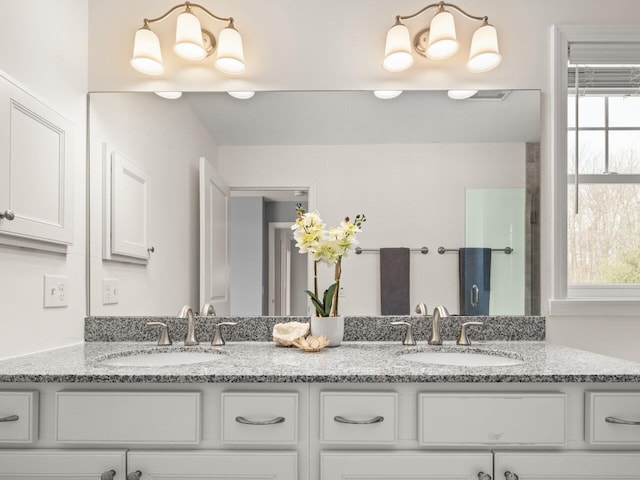 full bathroom featuring double vanity, visible vents, a shower with door, and a sink