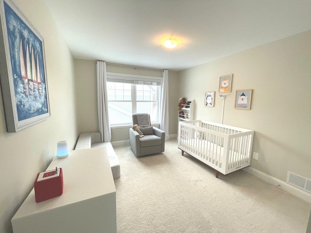 bedroom with visible vents, a crib, carpet, and baseboards