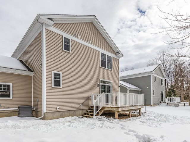 snow covered rear of property with central AC and a deck