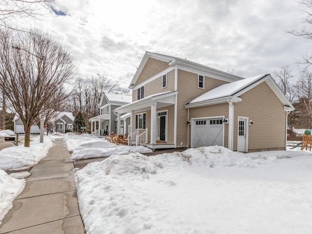 view of snowy exterior with an attached garage and covered porch