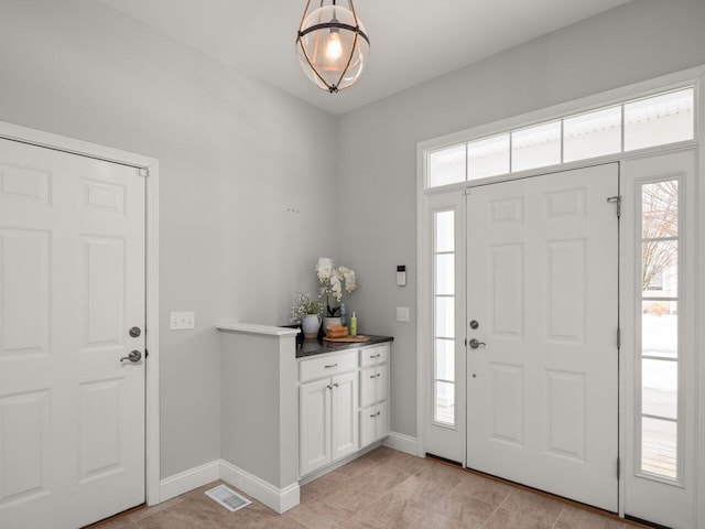 foyer with a wealth of natural light, visible vents, and baseboards