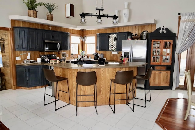 kitchen featuring a kitchen bar, dark cabinets, appliances with stainless steel finishes, and a kitchen island