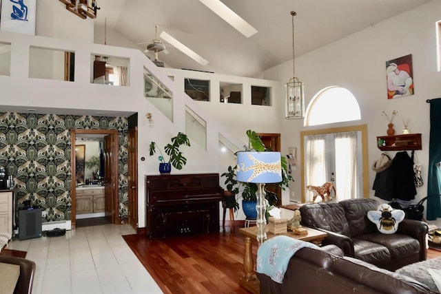 living area featuring high vaulted ceiling, a skylight, and wallpapered walls