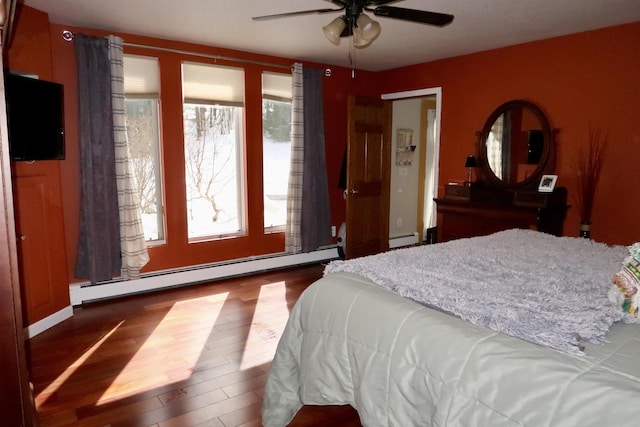 bedroom featuring ceiling fan, a baseboard heating unit, and wood finished floors