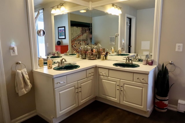 bathroom featuring double vanity, baseboards, and a sink