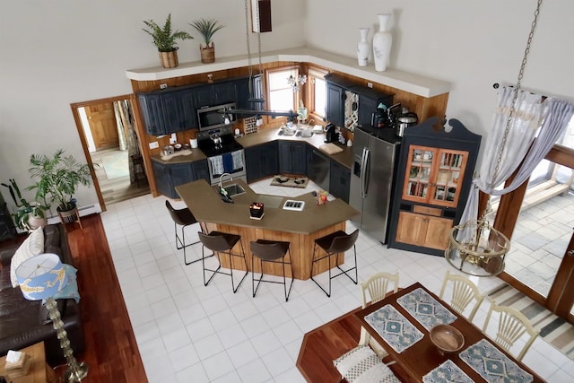 kitchen with light tile patterned floors, a sink, stainless steel appliances, a kitchen bar, and a center island