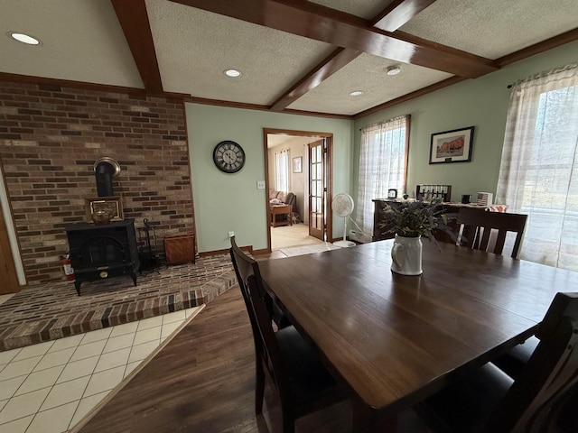 dining room with beamed ceiling, a healthy amount of sunlight, a textured ceiling, and a wood stove