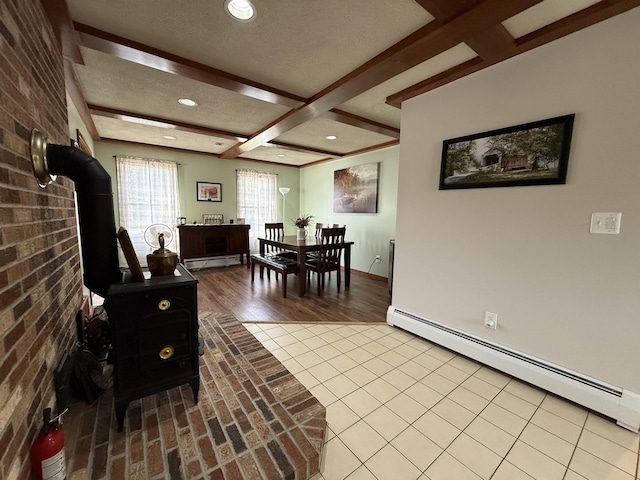 tiled dining room featuring beam ceiling, a baseboard heating unit, brick wall, baseboard heating, and a wood stove