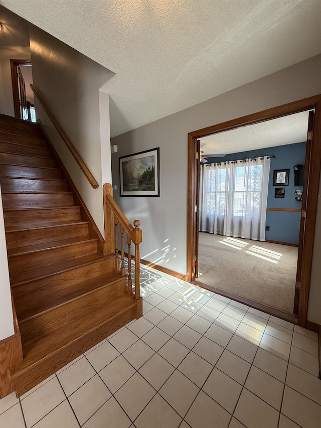 interior space featuring tile patterned floors, carpet flooring, a textured ceiling, and baseboards