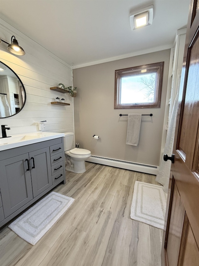 full bath featuring toilet, ornamental molding, wood finished floors, baseboard heating, and vanity