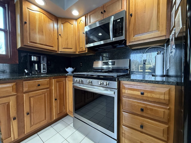 kitchen with light tile patterned flooring, decorative backsplash, appliances with stainless steel finishes, and brown cabinetry