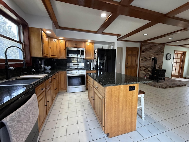 kitchen with light tile patterned floors, stainless steel appliances, a wood stove, and a sink