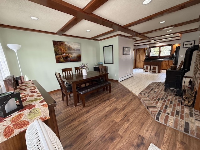 dining area featuring light wood finished floors, baseboard heating, a textured ceiling, and a wood stove