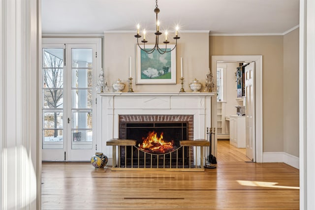 living room with a brick fireplace, crown molding, baseboards, and wood finished floors