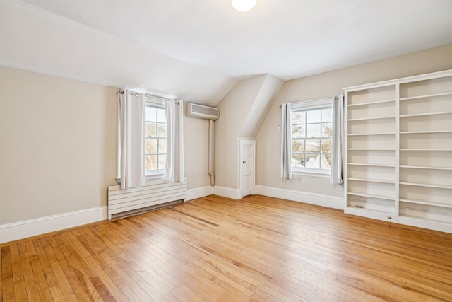 bonus room with baseboards, light wood-type flooring, and a wealth of natural light