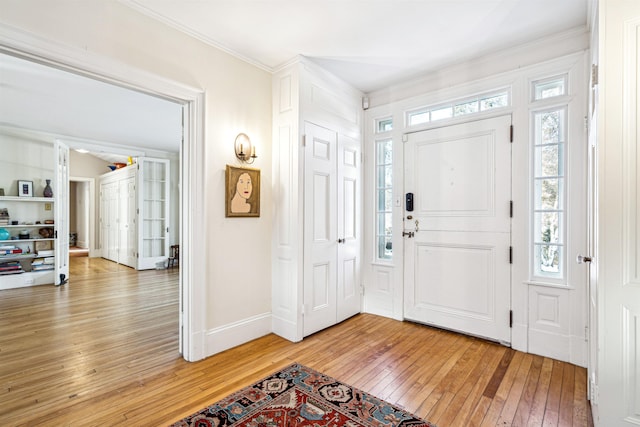 entryway featuring crown molding, light wood-style floors, and baseboards