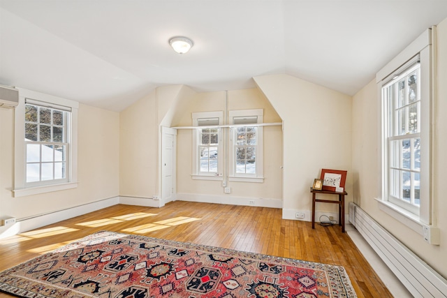 bonus room with light wood-style floors, plenty of natural light, baseboard heating, and vaulted ceiling