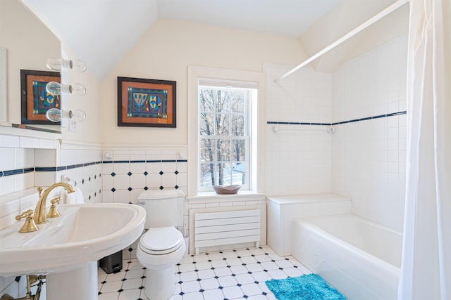 full bath featuring toilet, vaulted ceiling, shower / bath combination with curtain, tile walls, and a sink