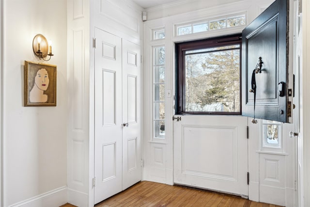 doorway with light wood-style floors and ornamental molding