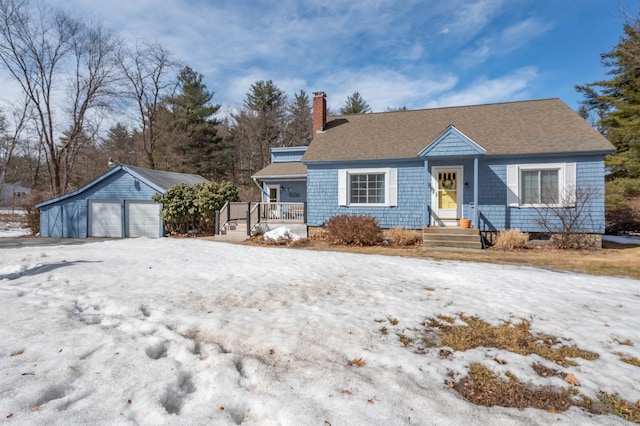 view of front of property featuring a garage, an outbuilding, a chimney, and a shingled roof