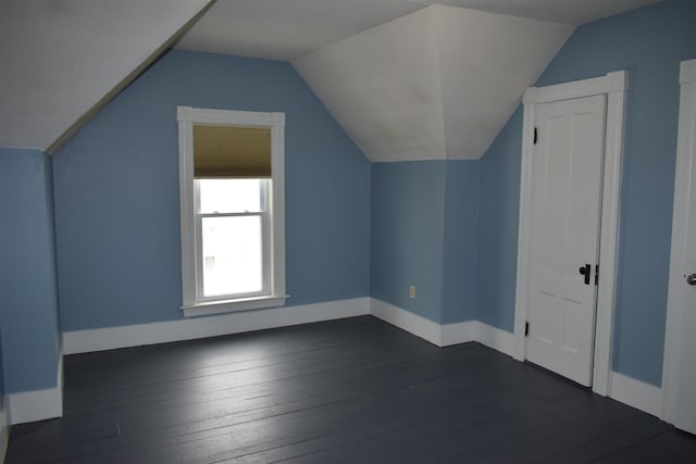 additional living space featuring baseboards, dark wood-type flooring, and lofted ceiling