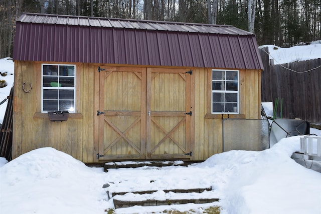 snow covered structure with an outbuilding and a shed