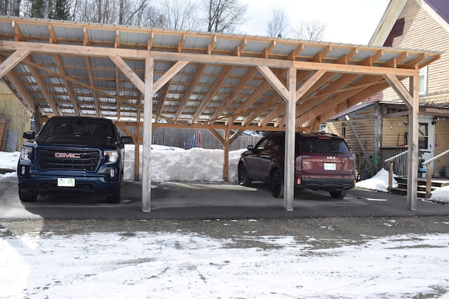 snow covered parking area featuring a carport