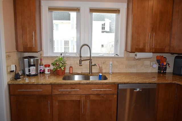 kitchen with light stone countertops, decorative backsplash, stainless steel dishwasher, brown cabinetry, and a sink