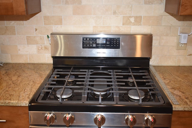 details featuring stainless steel gas range oven, brown cabinets, and tasteful backsplash