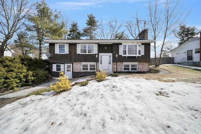 split foyer home featuring a chimney and fence