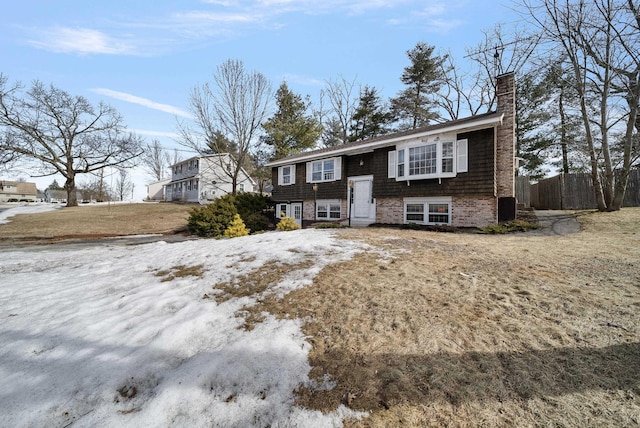 split foyer home featuring fence and a chimney