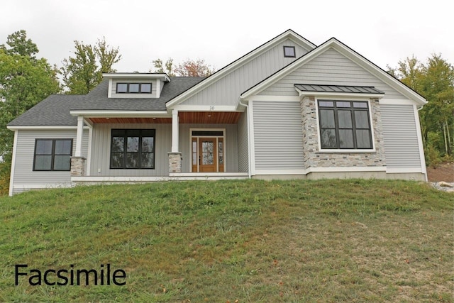 view of front of home with board and batten siding, a front lawn, and a shingled roof