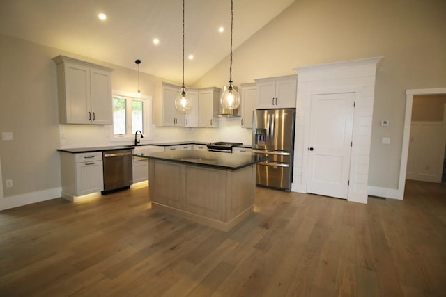 kitchen with a kitchen island, dark wood-style flooring, appliances with stainless steel finishes, pendant lighting, and dark countertops