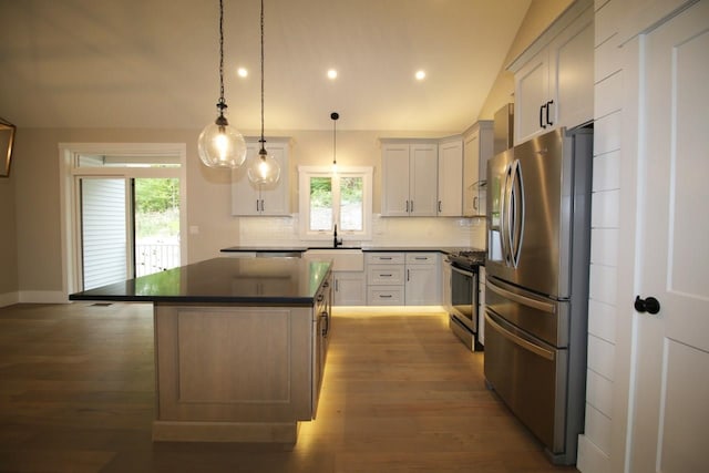 kitchen featuring tasteful backsplash, dark countertops, a center island, stainless steel appliances, and lofted ceiling