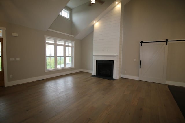 unfurnished living room with visible vents, a large fireplace, baseboards, wood finished floors, and high vaulted ceiling