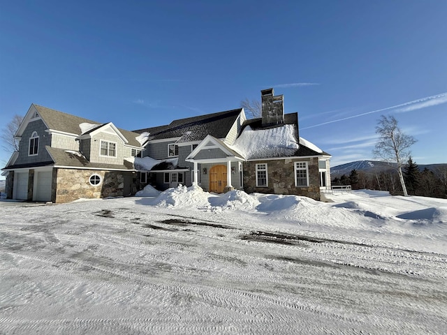 view of front of house with stone siding, a chimney, and a garage