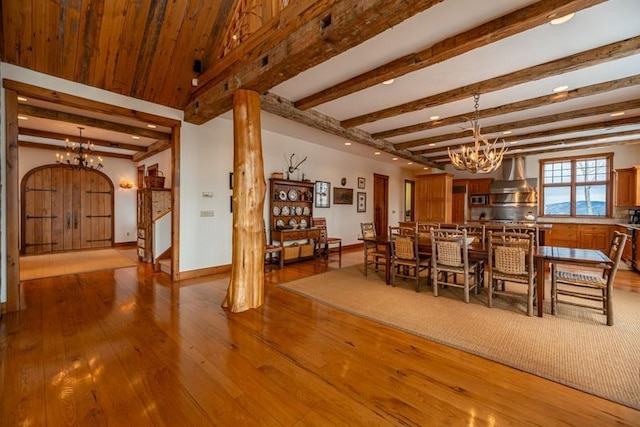 unfurnished dining area with baseboards, arched walkways, a notable chandelier, and wood-type flooring