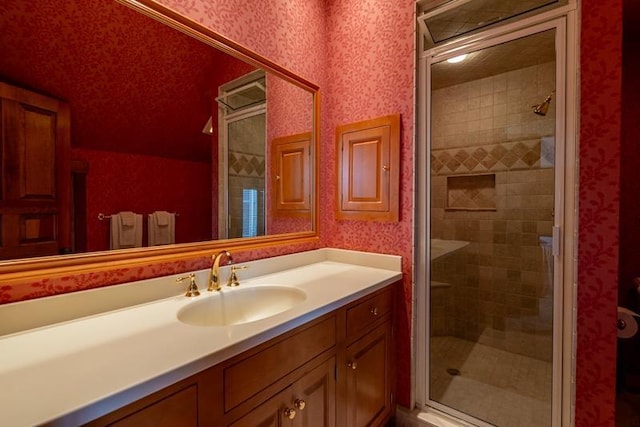 full bathroom featuring a stall shower, vanity, and wallpapered walls