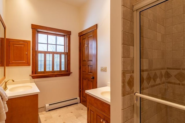 full bath featuring two vanities, a stall shower, baseboard heating, and a sink