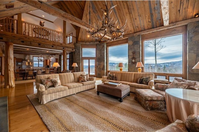 living room featuring wood finished floors, high vaulted ceiling, beam ceiling, wooden ceiling, and a notable chandelier