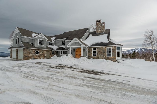 view of front facade with stone siding, an attached garage, and a chimney