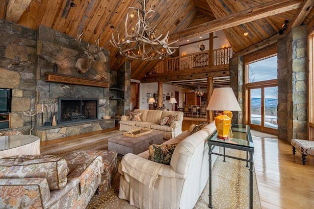 living room featuring a chandelier, a stone fireplace, wood ceiling, and wood finished floors