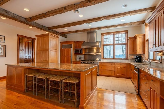 kitchen with tasteful backsplash, a kitchen island, wall chimney range hood, stainless steel appliances, and a sink