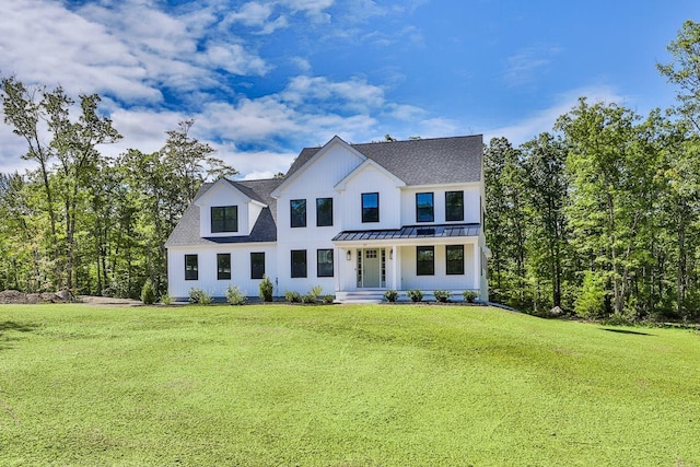 modern farmhouse style home with board and batten siding, a shingled roof, a front yard, metal roof, and a standing seam roof