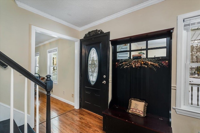 foyer with baseboards, ornamental molding, stairs, wood-type flooring, and a textured ceiling